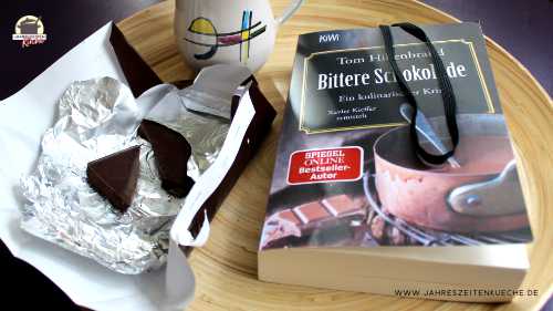 Das Buch Bittere Schokolade liegt mit einer aufgerissenen Schokoladentafel auf einem Tablett