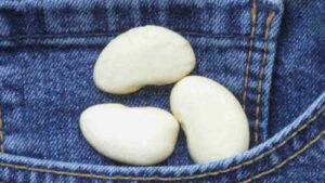 3 weiße Bohnen liegen auf einer Jeans