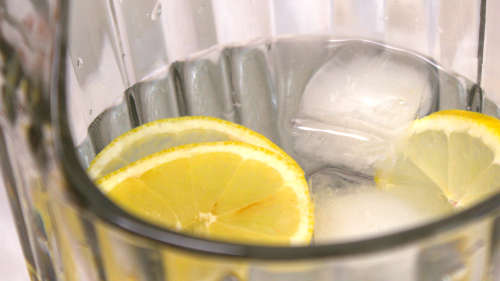Ein Krug mit Wasser. Darin sind Zitronenscheiben und Eiswürfel