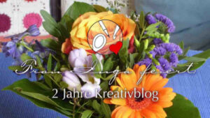 Ein Blumenstrauß mit Rosen. Darauf steht: "Frau Inga feiert: 2 Jahre Kreativblog."