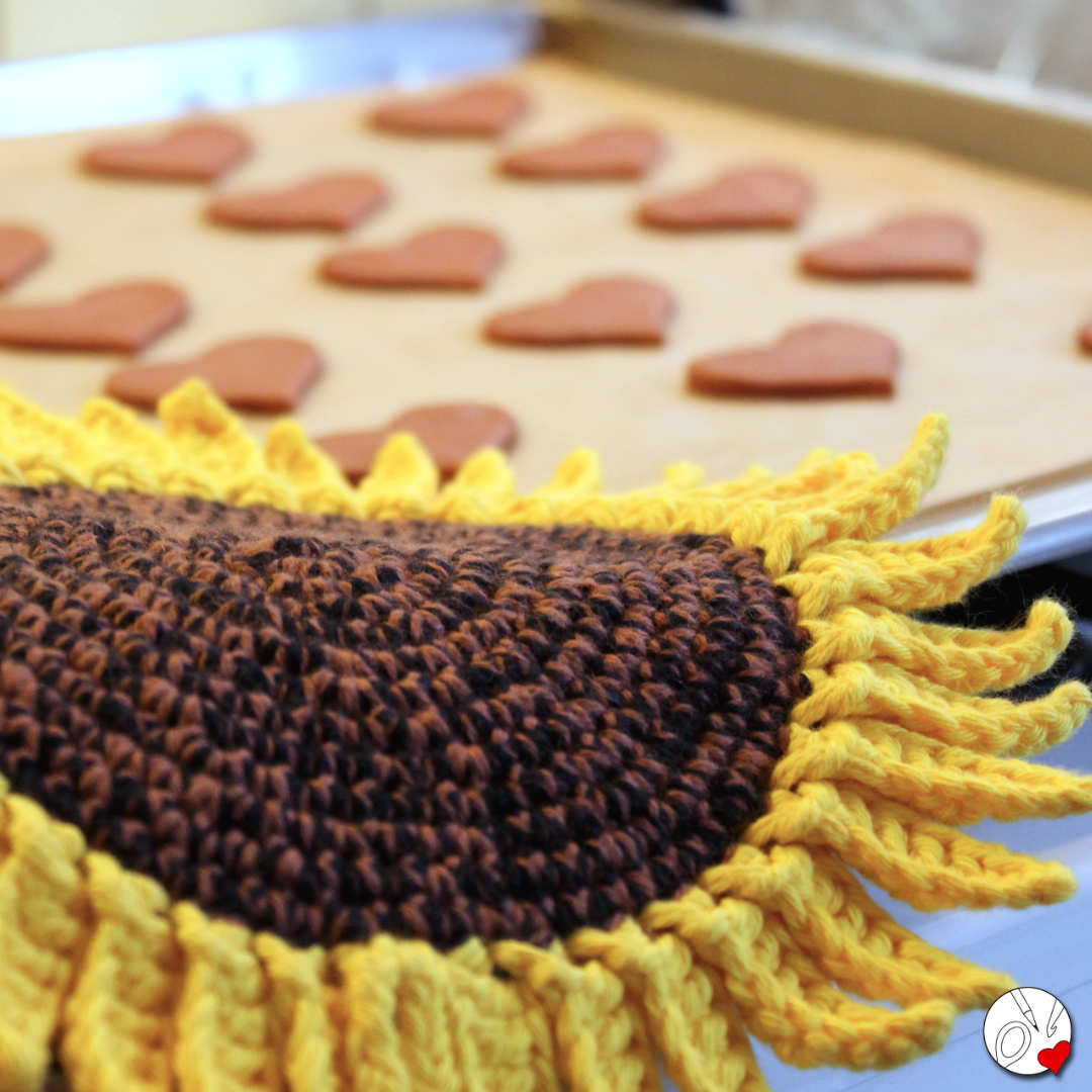 Auf einem Backblech mit Keksen liegen Sonnenblumen-Topflappen