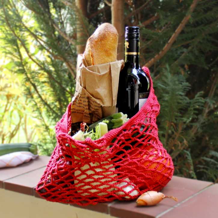 Mandala-Häkelnetz mit Brot, Gemüse und einer Flasche Wein
